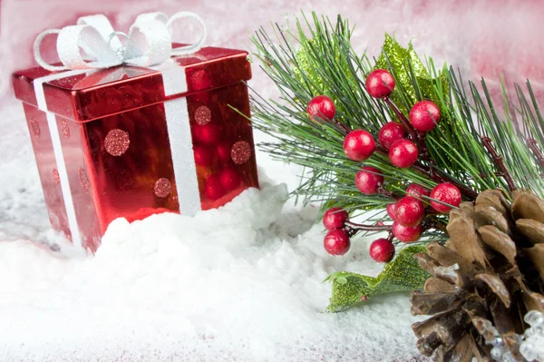 Caixa vermelha e folhas de Natal na neve — Fotografia de Stock