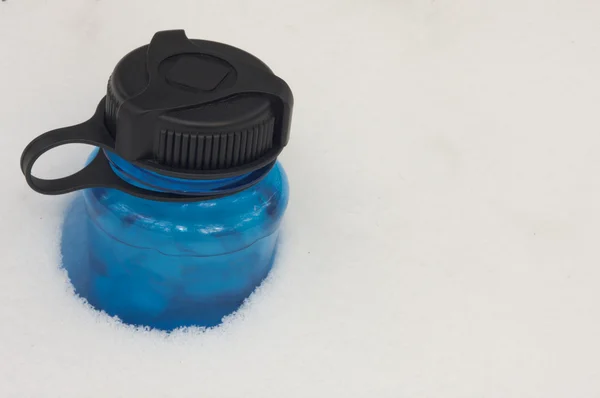 Botella de agua deportiva azul en la nieve —  Fotos de Stock