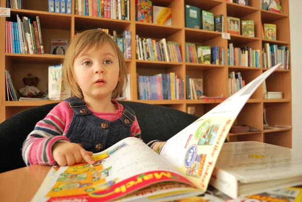 Menina lendo em uma biblioteca — Fotografia de Stock