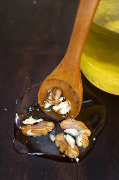 Wallnuts i honung på trä bakgrund med träsked och hon — Stockfoto