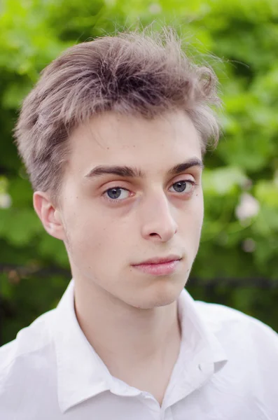 Portret van mooie jonge man op groene natuurlijke achtergrond. — Stockfoto