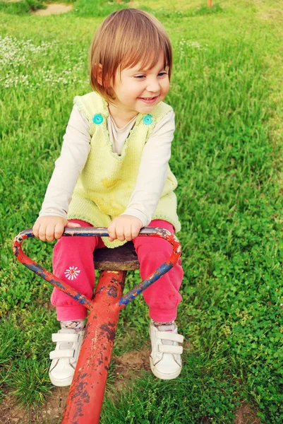 Fröhliches kleines Mädchen schwingt auf der Säge — Stockfoto