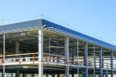 Yeni bir modern endüstriyel binanın bitmemiş metal iskeleti mavi gökyüzüne karşı kamu hizmetleri ile