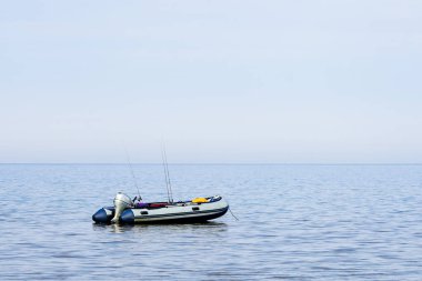Terkedilebilir, deniz suyunda motoru olan, balıkçı çubukları olan ve insansız, şişme lastik bir tekne.