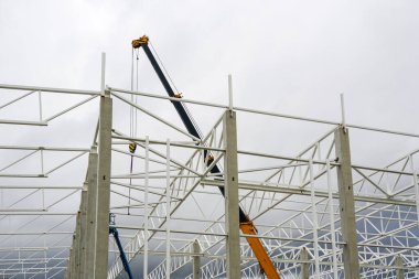 Yeni bir modern endüstriyel binadaki metal yapıların montajında teleskopik bir patlama olan bir vinç.