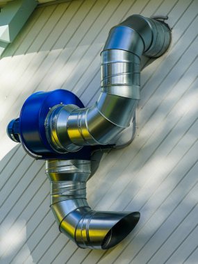 Tahta kafe binasının arkasında elektrikli motor ve metal boruları olan basit bir havalandırma ünitesi.