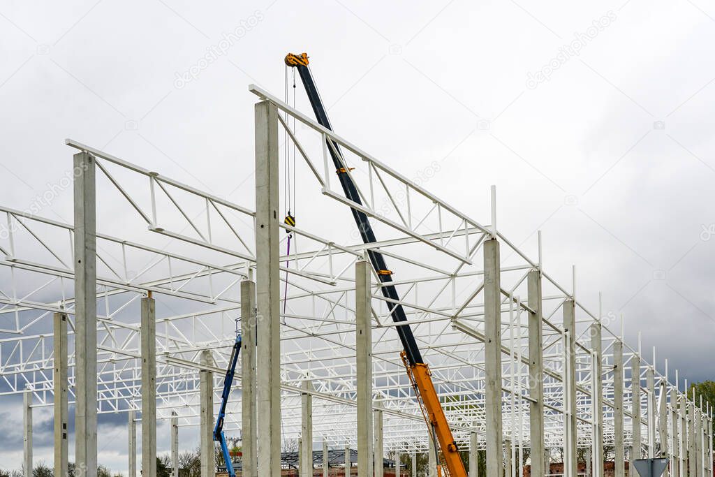 a crane with a telescopic boom in the assembly of metal structures in a new modern industrial building