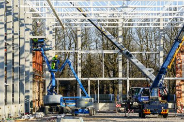 Yeni bir binada metal yapısal çerçevelerin montajı ve kurulumu için kendinden itişli makas asansörleri ve teleskopik vinç