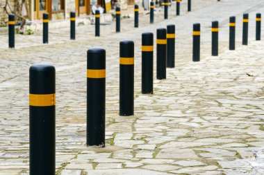 Siyah ve sarı direkli asfaltlı kaldırım koruması.