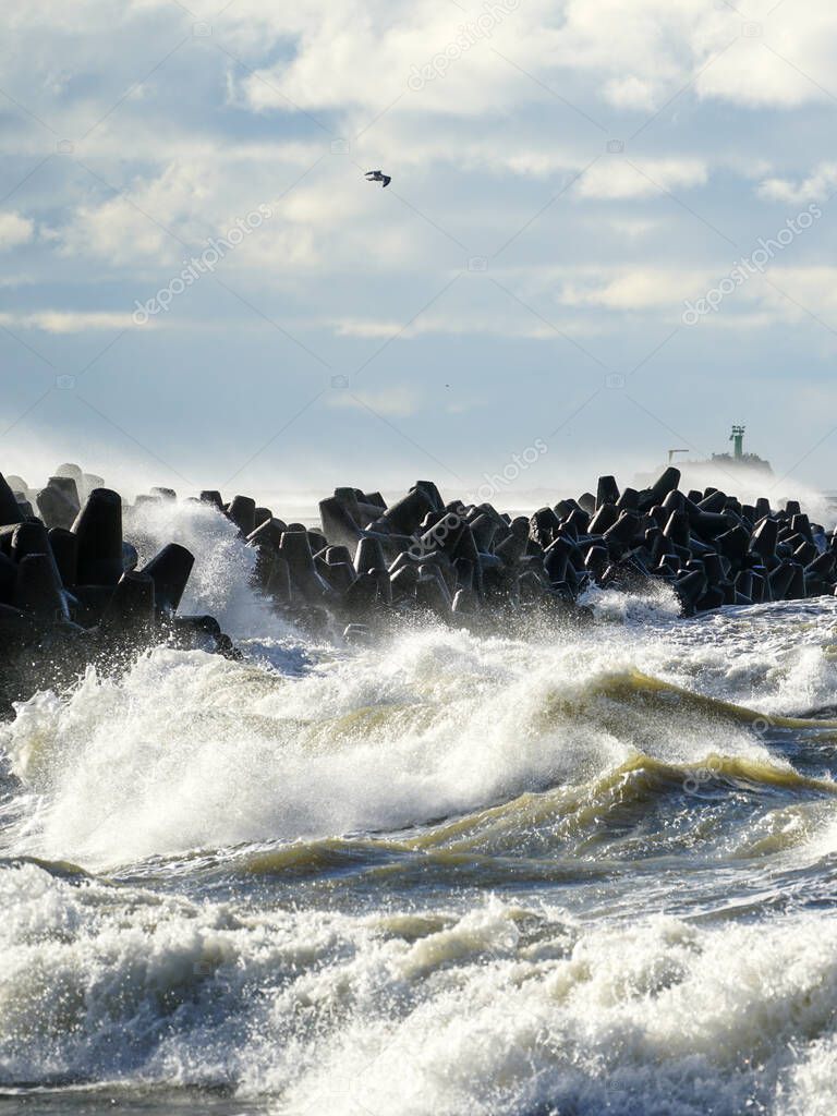 coastal storm in the Baltic Sea, big waves crash against the concrete breakwater at the port entrance