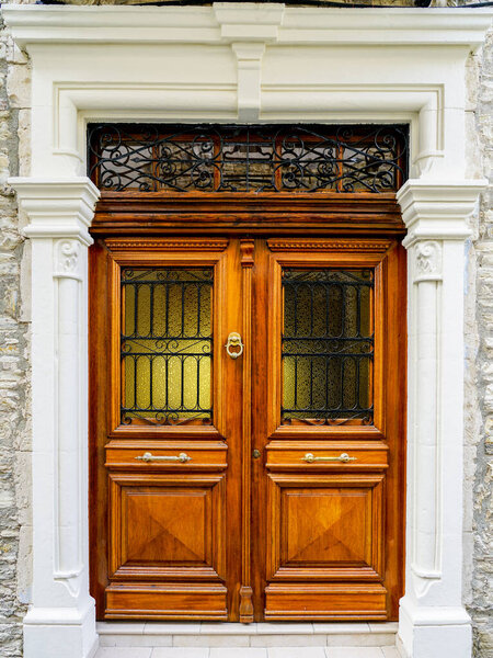 beautiful historical luxury brown wooden double front door with wrought iron ornaments and a beautiful white stylized pediment