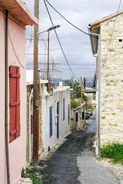 Kıbrıs 'ta kısmen ıssız, küçük bir dağ köyünde antik kireçtaşı duvarları olan romantik dar bir sokak manzarası