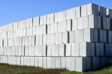 Beton bir fabrikanın arka bahçesindeki büyük beton blok yığınları mavi gökyüzüne ve sarı vinç patlama arka planına karşı.