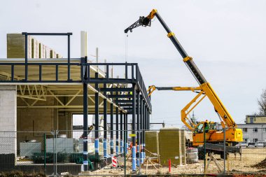 Teleskopik patlama vinci ve itici kaldıracı kullanan beton bloklardan ve metal yapılardan oluşan modern bir binanın montajı
