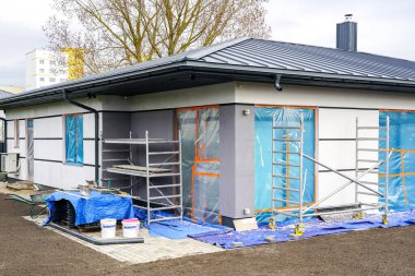 Tamamlanmamış, prefabrik, gri metal çatılı, tek katlı özel bir ev.