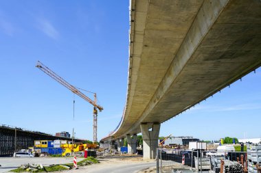 Mavi gökyüzü arka planında sarı kule vinci olan yeni modern yol üstgeçidi beton köprü şantiyesi