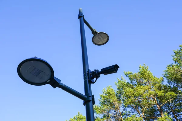 Modern design equipment for park infrastructure, led lamps and a surveillance system camera on a metal pole