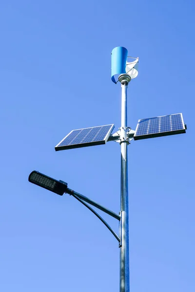 Pole with innovative LED street light powered by solar cells and small vertical wind generator, blue sky background