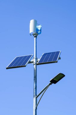 Pole with innovative LED street light powered by solar cells and small vertical wind generator, blue sky background