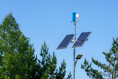 Pole with innovative LED street light powered by solar cells and small vertical wind generator, blue sky background