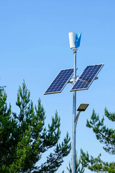 Pole with innovative LED street light powered by solar cells and small vertical wind generator, blue sky background