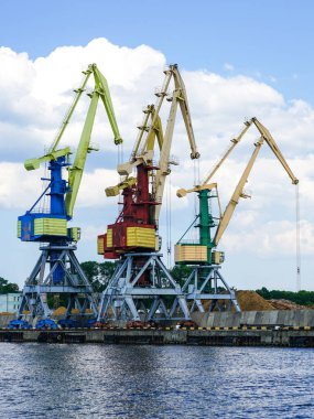 Bulk cargo terminal in port with many shore cranes and piles of coal and wood chips