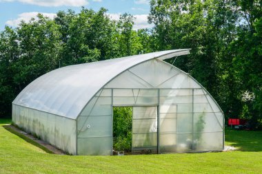 Yazın kırsal alanda açık pencereli basit geniş plastik sera.