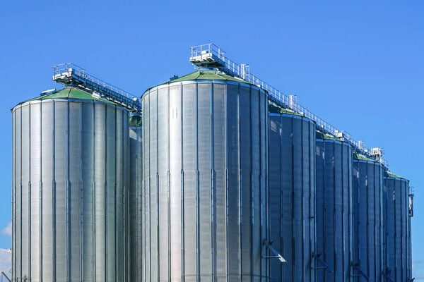 Agricultural silos, storage and drying of grains, wheat, corn, soy, sunflower against the blue sky background, grain dryer