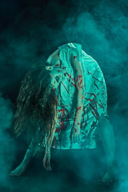 Korkunç şekilsiz bir kadın, şeytan tarafından ele geçirilmiş, kanlı bir gece kıvrımında, karanlıkta duruyor, dumanla çevrili. Ürkütücü zombi kadın. Korku, gerilim. Cadılar Bayramı.
