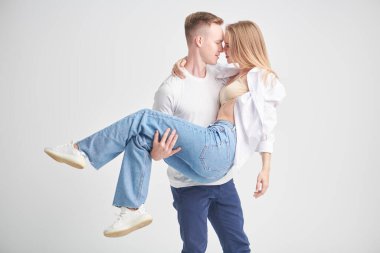 Mutlu genç adam beyaz bir stüdyoda sevgili kız arkadaşını kollarında tutuyor. Aşk ilişkisi. 