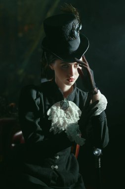 19. yüzyıldan kalma bir elbise giymiş, eskimiş bir odada poz veren kendine güvenen genç bir kadının portresi. 19. yüzyılın sonları - 20. yüzyıl başları. 