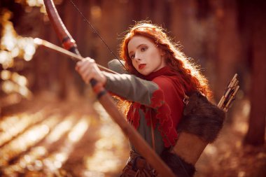Orta Çağ 'ın cesur kızıl saçlı okçusunun portresi ok ve yayla ormanı hedef alıyor. Hayal dünyası..