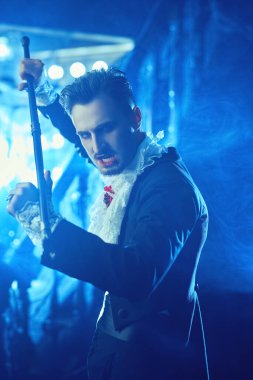 Şeytani kana susamış vampir sihirli değneğiyle saldıracak. Eski kasvetli şatonun arka planında gizemli bir sis var. Cadılar Bayramı. Vampirler. Boşluğu kopyala.