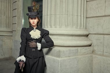 Şehir caddesinde yürüyen siyah elbiseli ve şapkalı güzel bir hanımın portresi. 19. yüzyılın sonları, 20. yüzyılın başları. Boşluğu kopyala.