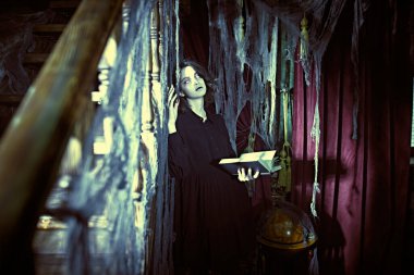 Kütüphane hayaleti. Terk edilmiş eski bir evde yalnız ve üzgün bir hayalet kız elinde bir kitapla duruyor. Dehşet. Cadılar Bayramı.