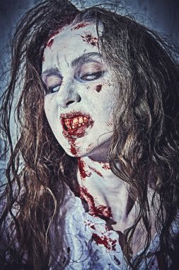 A horrible zombie woman with faded eyes bares her bloody teeth. Devil possessed woman. Horror, thriller. Halloween.  clipart