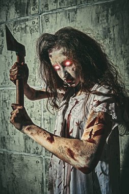 Yanan gözlü, tüylü tüylü korkunç zombi kadın kanlı bir gecelikle elinde kanlı bir baltayla ayakta duruyor. Saplantılı kadın. Korku, gerilim. Cadılar Bayramı. 