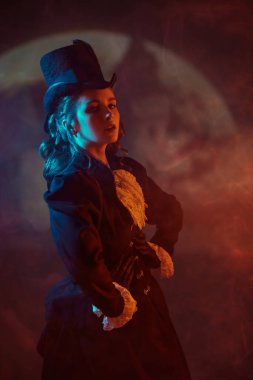 19. yüzyıldan kalma takım elbiseli güzel bir bayan dolunay, sis ve kırmızı ışıkla karanlık ve gizemli bir arkaplanda poz veriyor. Vampirler. Cadılar Bayramı.