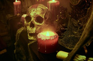 Kara büyü konsepti. Karanlık bir odada mumlarla çevrili kanlı bir insan kafatasının portresi. Cadılar Bayramı.