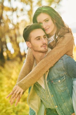 Birbirine aşık gençler. Sonbahar parkında yürürken güzel kız arkadaşını sırtında taşıyan yakışıklı bir genç. Güneşli bir sonbahar günü.