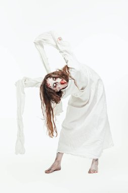 Korku, gerilim. Cadılar Bayramı. Kana bulanmış soluk gözlü ve dağınık saçlı deli, şeytan ruhlu bir kadın beyaz bir duvara karşı deli gömleği giyiyor. Zombi kadın.. 