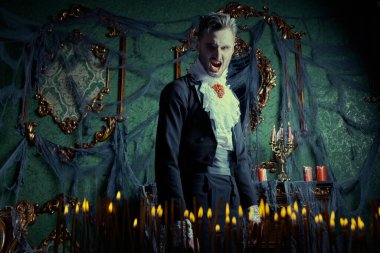 Kana susamış vampir öfkeyle homurdanıyor, yanan mumların arasında sivri dişlerini göstererek karanlık ve kasvetli kalesini aydınlatıyor. Cadılar Bayramı.