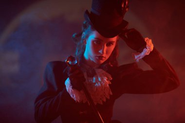 19. yüzyıl elbisesi giymiş güzel bir bayan dolunay, sis ve kırmızı ışıkla karanlık, gizemli bir arka planda duruyor. Vampirler. Cadılar Bayramı.