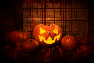 Cadılar Bayramı kartpostalı. Korkunç balkabağı ahşap bir evde yatıyor. Duvarın arka planında kan izleri var..