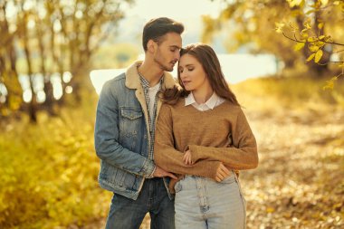 Birbirlerine aşık güzel genç insanlar nehir kenarında birlikte yürüdükleri harika bir sonbahar gününün tadını çıkarıyorlar. Aşk ve ilişki.