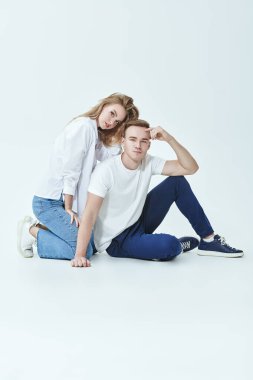 Güzel bir kız ve erkek yan yana oturan beyaz bir arka planda poz veriyorlar. Tam yol ileri. Aşk ve ilişki.