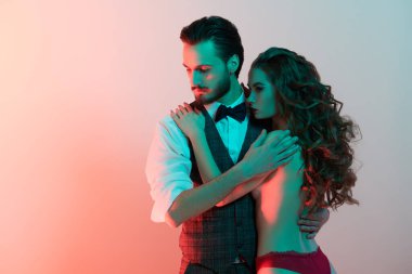 Zarif takım elbiseli ve papyonlu yakışıklı, tutkulu bir adam seksi, çıplak bir kıza sarılıyor. Aşk ve moda. Boşluğu kopyala.