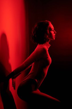 Çekici, kıvırcık saçlı, siyah arka planda beyaz tulumlu güzel bir manken kızı portresi. Seksi kadın portresi.