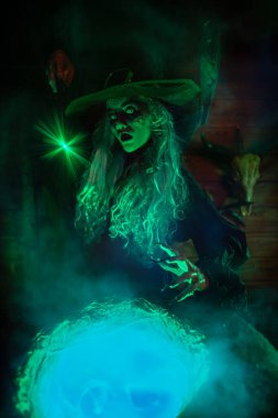 Yaşlı, korkunç bir cadı elinde sihirli bir değnekle cadı iksiri hazırlıyor. Cadılar Bayramı korkunç hikayeleri.