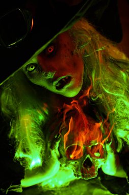Korkunç kötü bir cadı ininde bir iksir yapar ve elinde bir kafatası tutar. Sihirli yeşil ışık. Cadılar Bayramı. 